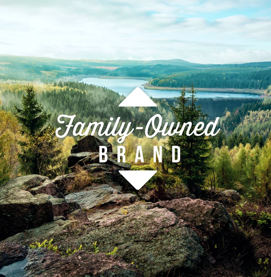 A collection of large rocks overlooking a forest of pine trees with the words ‘Family-Owned Brand’ overlaid.